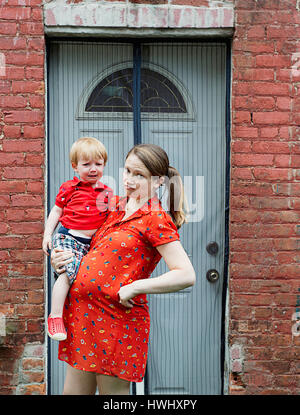 A pregnant woman holding her crying child Stock Photo