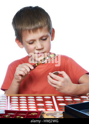 Boy examines a collector silver coin through a magnifying glass isolated white Stock Photo