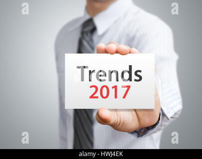 Businessman showing trends 2017 wording on white card Stock Photo