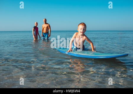 Athletic family with little boy teaching him surfing Stock Photo