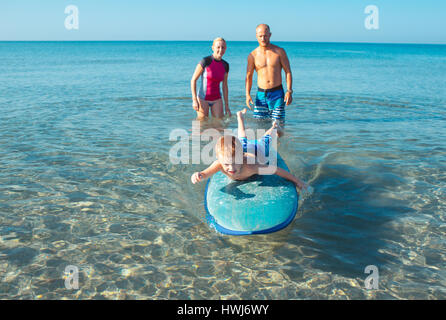 Athletic family with little boy teaching him surfing Stock Photo