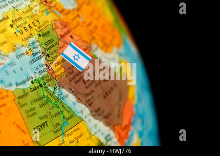 map with miniature flag of Israel .Selective focus on Israeli Flag.  Detail Globe Backlit lighting Stock Photo