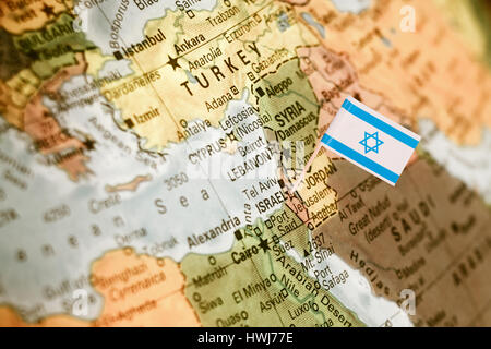map with miniature flag of Israel .Selective focus on Israeli Flag.  Detail Globe Backlit lighting Stock Photo