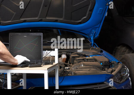 Mechanic testing car engine with laptop application. Inspection  electric vehicle Stock Photo