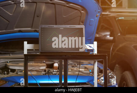 Car garage diagnostic station with computer table on blue blurred vehicle background Stock Photo
