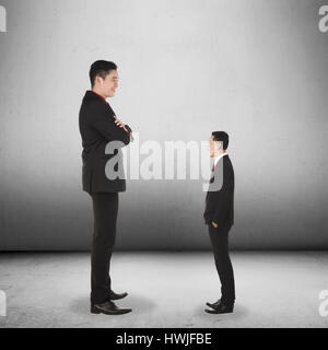 Small businessman looking at his big boss on grunge background Stock Photo