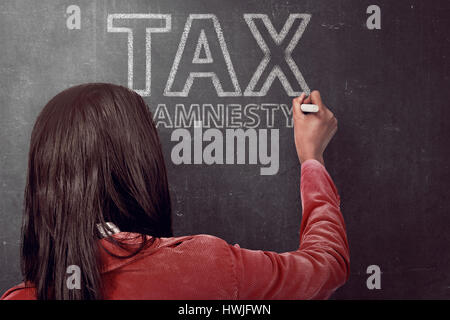 Business woman writing tax amnesty quotes on the black board with chalk Stock Photo