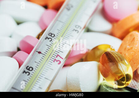 Thermometer and different colored types of pills. Medical health or drugs concept. Stock Photo