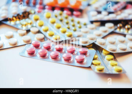 Pills of different colors lie on the surface in a sealed package Stock Photo