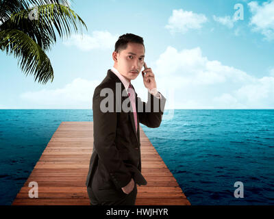 Young asian business man taking cellphone on the wooden pier Stock Photo