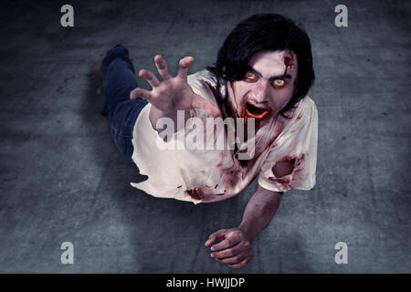 Male zombie crouching on the floor. Halloween concept Stock Photo