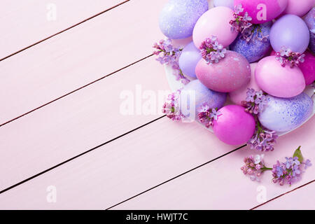Easter eggs and  lilac  flowers (Syringa) on pink wooden table.  View from above. Stock Photo