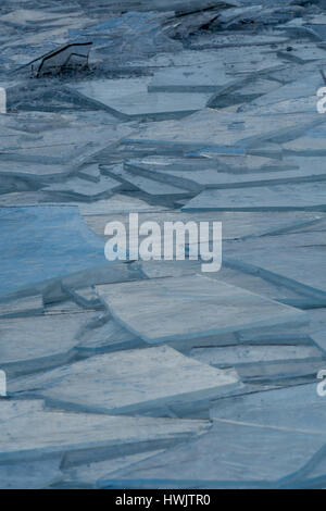 Broken ice piled up by wave action on shore of a lake. Stock Photo