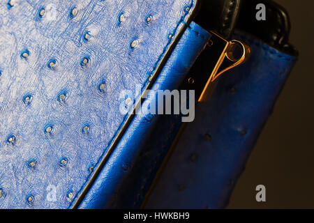 Close-up texture of fashion blue color handbag from genuine leather, embossed under skin Ostrich, gold detal for strap. Concept of shopping, manufacturing, lifestyle Stock Photo