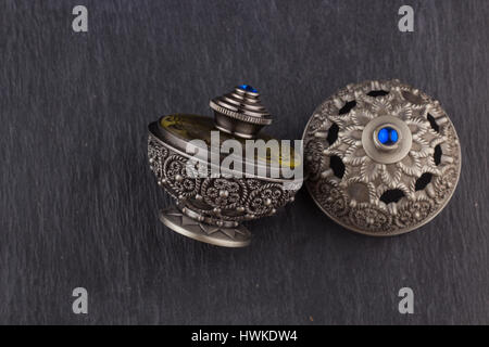 Silver Oriental Artistic Arabian Oud Perfume / Arabian Oud Perfume with Oud Scented Wood burned in the background with Scented Smoke in the Air Stock Photo