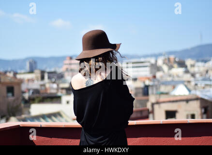 Lonely young woman in brown hat from the back thinking on terraсe, Barcelona, gothic quarter Stock Photo