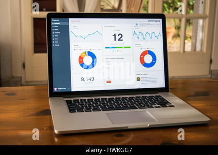 Silver laptop with analytical graph on the screen on the wooden table in home interior Stock Photo