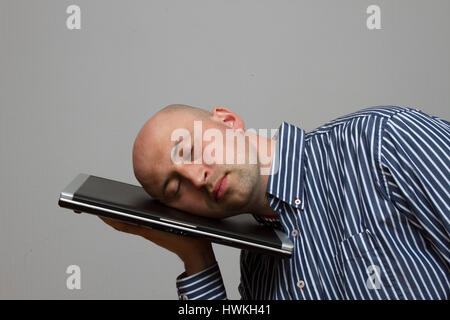 Businessman tiring and sleeping on his laptop in outdoor scene - overworked concept Stock Photo