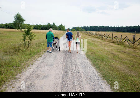 Polish couple 19 and 18 walking with neighbor who is a father age 41 pushing stroller with baby 7 months. Zawady Central Poland Europe Stock Photo