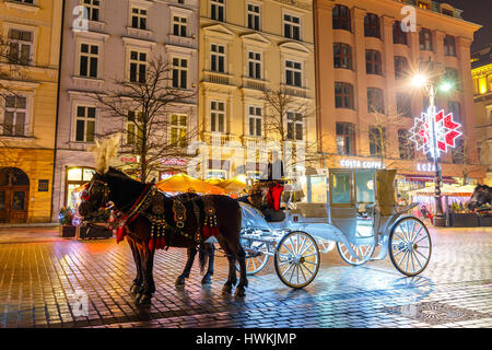 Krakow, Poland - January 22, 2017: Horse-drawn Carriage before the Sukiennice on The Main Market Square in Krakow, night view, Poland Stock Photo
