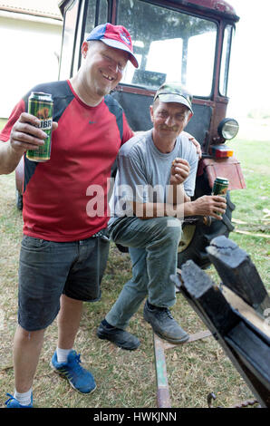 Two men taking a beer break in front of their tractor   after a morning of hard work age 41 & Polish farmer age 53. Zawady Central Poland Europe Stock Photo