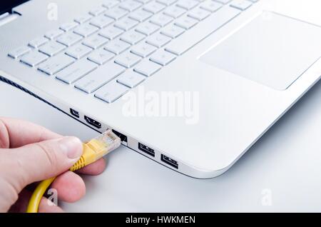 Hand connecting ethernet cable to lan port Stock Photo