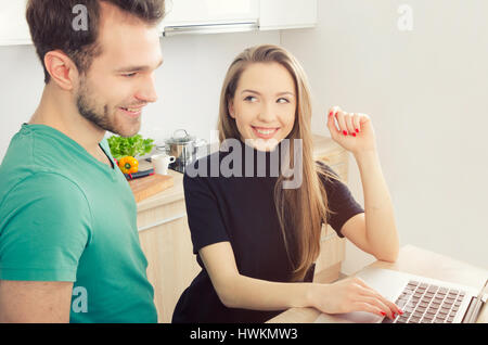 Couple uses the computer in the kitchen. lifestyle couple kitchen cooking home happy breakfast young concept Stock Photo