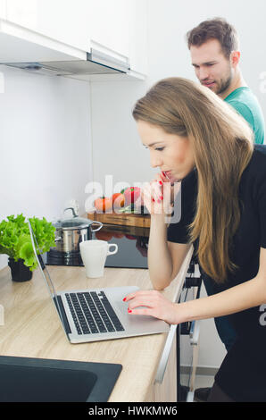 Young couple cooking together in the kitchen. kitchen couple cooking home food recipe laptop website concept Stock Photo
