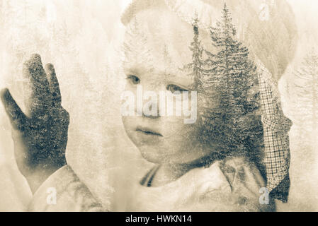 Little boy daydreaming, looking out the window at nature, thinking about it. Double exposure of child portrait and forest landscape. Hope, dreaming, b Stock Photo