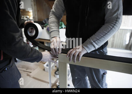 Workers preparing to install new three pane wooden windows in an old wooden house. Home renovation, sustainable living, energy efficiency concept. Stock Photo