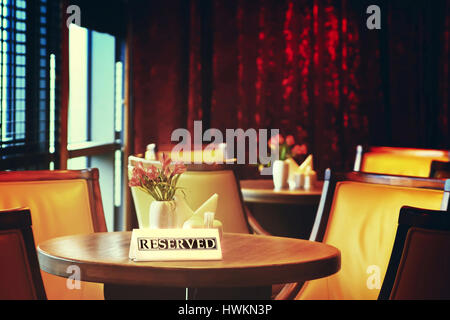 Reserved table close-up. Round wooden coffee table reserved. Relaxation background in warm tones. Stock Photo