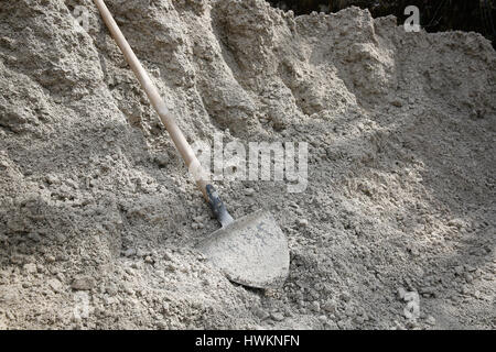 Shovel lying on a pile of construction sand and gravel for concrete mixing. Construction business and material, do-it-yourself, manual work, having a  Stock Photo