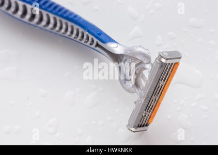 Disposable razor blade close up on white wet background with water drops Stock Photo