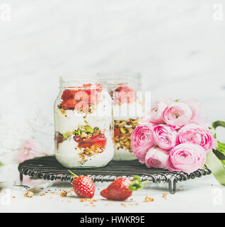 Healthy vegan spring breakfast jars with pink raninkulus flowers Stock Photo
