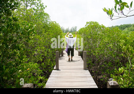 Traveler thai woman walking on wooden bridge for travel and visit Golden Mangrove Field thai name Tung Prong Thong Forest local Pak Nam Prasae town in Stock Photo