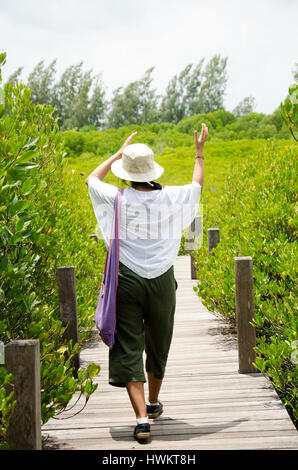 Traveler thai woman walking on wooden bridge for travel and visit Golden Mangrove Field thai name Tung Prong Thong Forest local Pak Nam Prasae town in Stock Photo