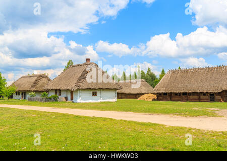 Rural road and old traditional houses with straw roof in Tokarnia village on sunny spring day, Poland Stock Photo