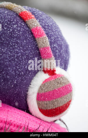 A woman wearing ear muffs and a woolly hat covered in raindrops Stock Photo