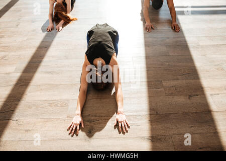 Top view of group of people practicing yoga on wooden floor in studio Stock Photo