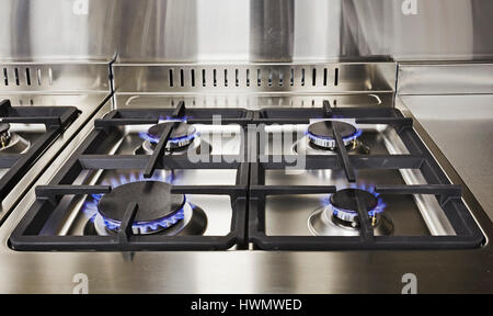 Burning blue flames of gas on cooktop under grills in a modern clean kitchen. Modern household appliance Stock Photo