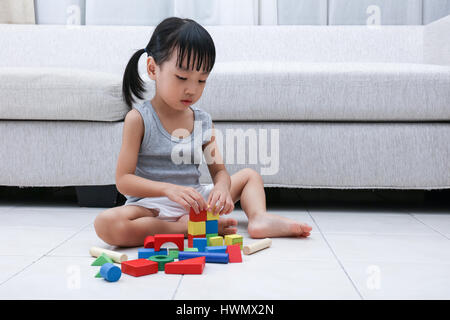 Asian Chinese little girl playing blocks on the floor in the living room at home. Stock Photo