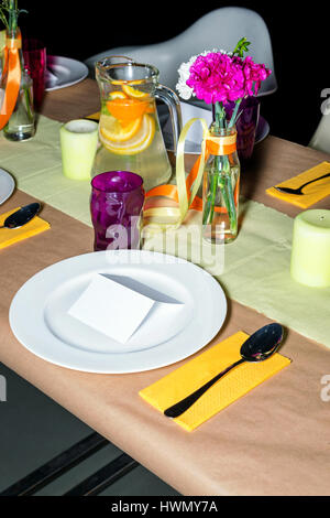 Decorated table in mexican style ready for dinner. Beautifully decorated colorful table set with flowers, candles, plates and serviettes for wedding or another event in the restaurant. Stock Photo