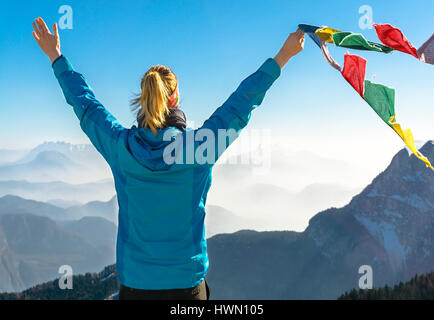 Happy success winning woman on summit arms up holding flag. Stock Photo