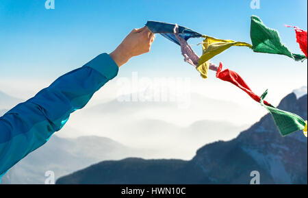 Female hand holds colored flags. Happy success reaching mountain summit. Stock Photo