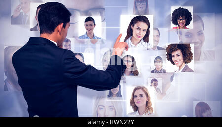 Thoughtful asian businessman pointing against grey background Stock Photo