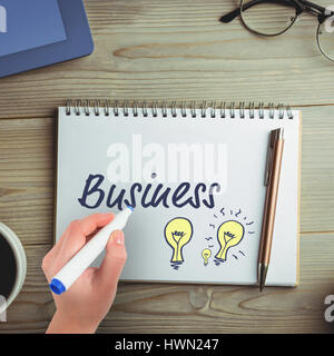 Businesswomans hand writing with marker against overhead view of coffee with office supplies Stock Photo