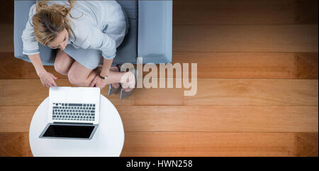 Woman on her laptop against wooden floor Stock Photo