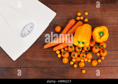 weighting scale against overhead view of various fresh vegetables on table Stock Photo