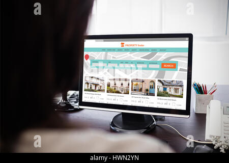 Composite image of property web site against  casual businesswoman working on laptop  Casual businesswoman working on laptop at office Stock Photo
