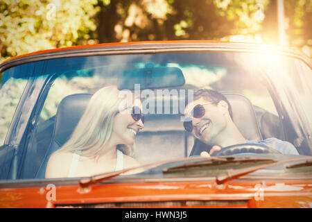 Loving couple in their red cabriolet having a ride on sunny day Stock Photo